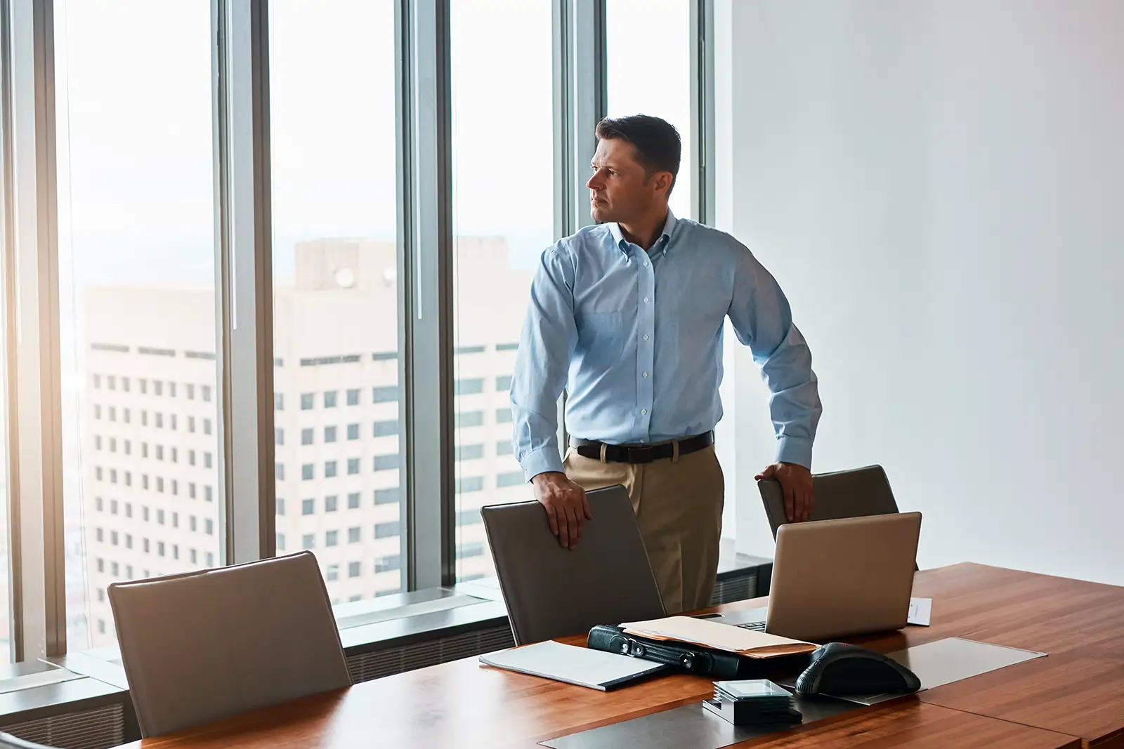 Executive standing alone in a boardroom after a meeting