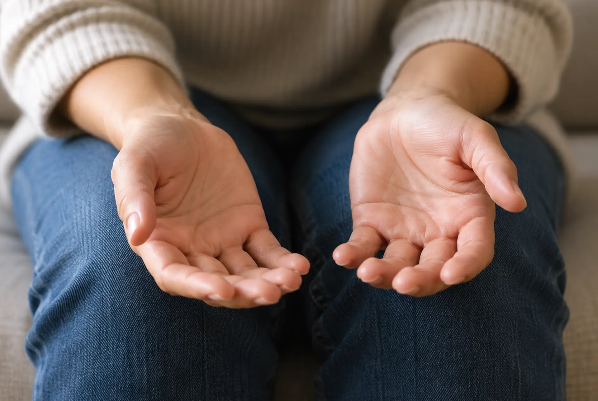 Close-up of open hands resting on a person's knees